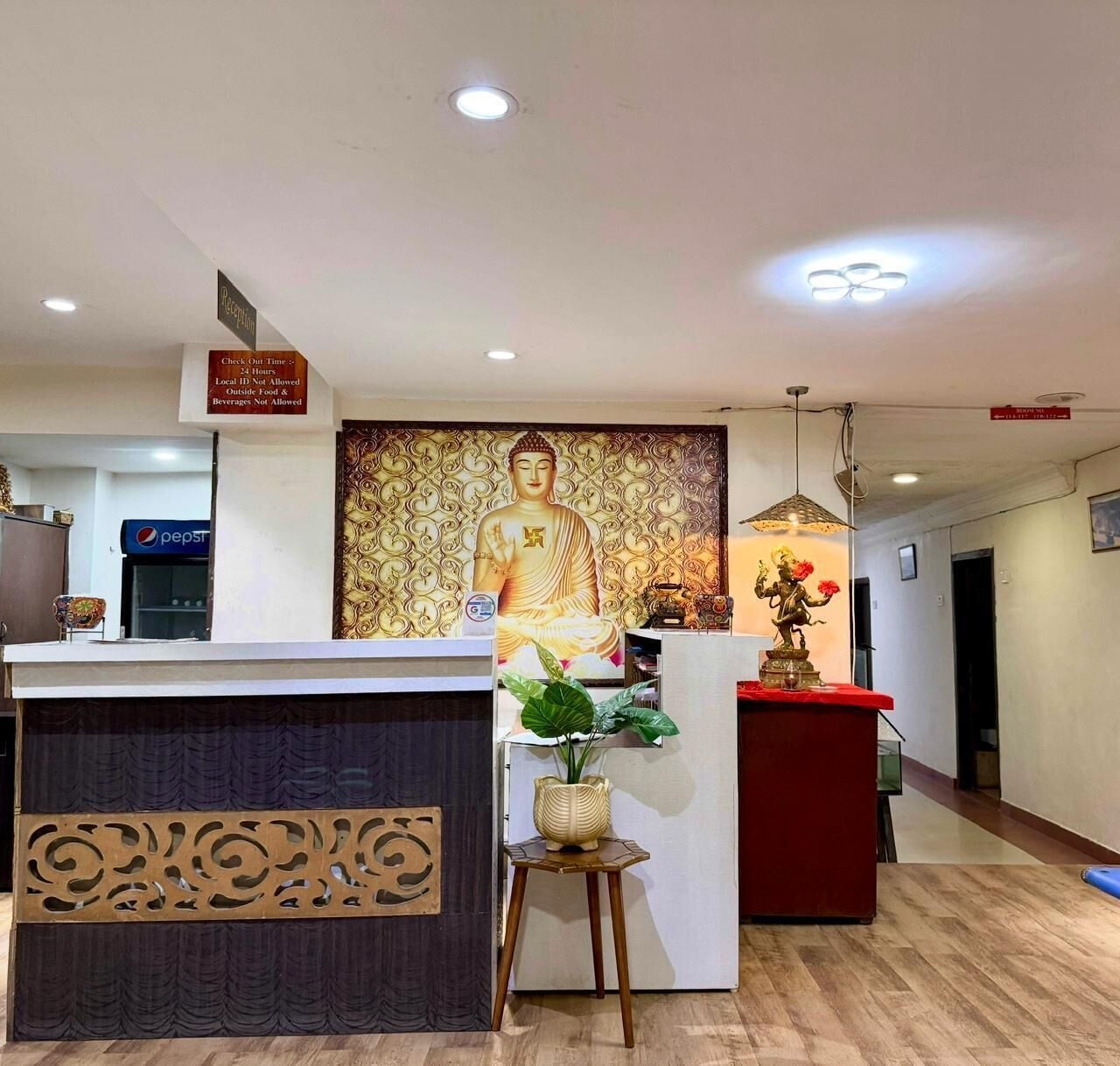 A reception area with a Buddha statue, a Pepsi refrigerator, and a check-out counter.