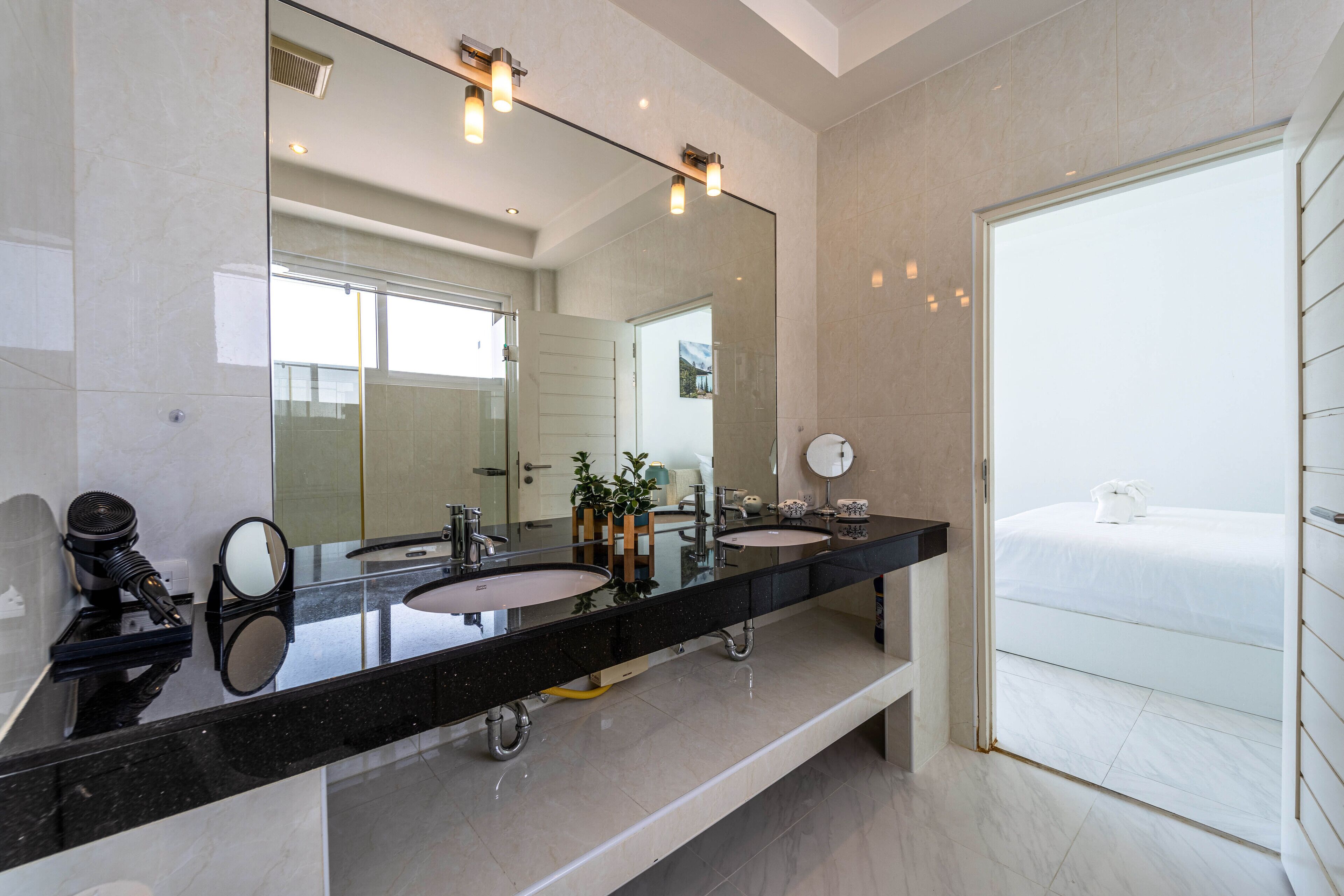 Un baño moderno con un espejo grande, dos lavamanos, un mueble de tocador y una bañera.