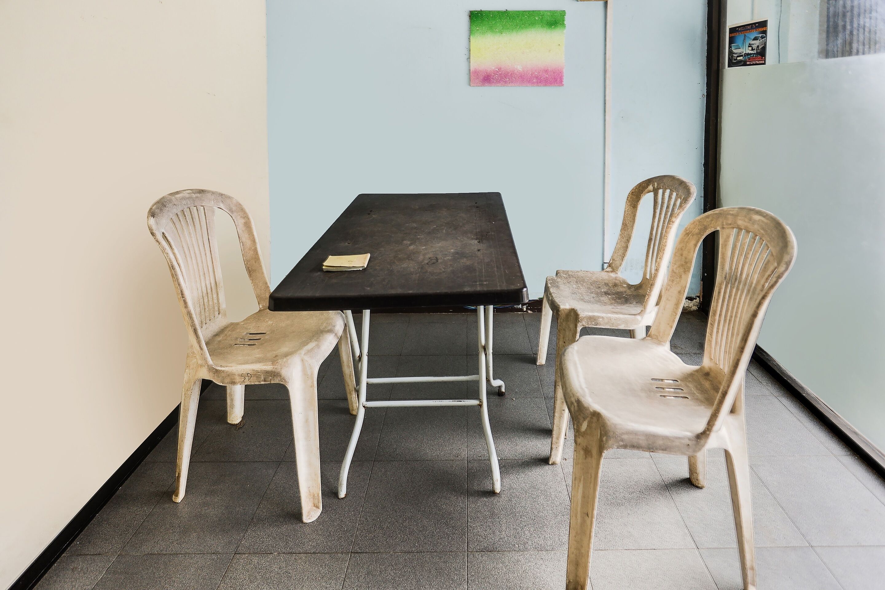 A small room with a black table and four plastic chairs.