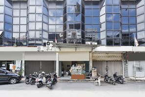 A modern building with a glass facade, a storefront with a variety of items on display, and several motorcycles parked in front. - Hotel O Ringin Pitu 2 SyariahNearAnugrah Sinar Lautan (Batam)