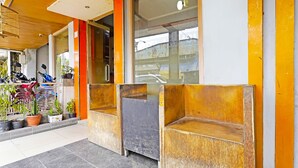 A building entrance with a tiled floor, a wooden bench, and potted plants. - SPOT ON 91444 Hotel Arimbi (Bandung)
