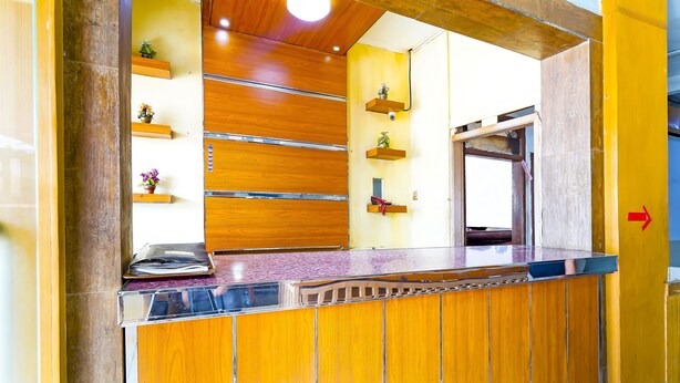A reception area with a wooden reception desk, a counter, and a wall-mounted telephone. - SPOT ON 91444 Hotel Arimbi (Bandung)