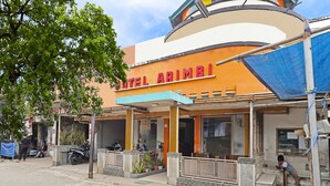 A hotel named "HOTEL ARIMBI" with a curved facade, a signboard, and a small entrance area with steps leading up to the door. - SPOT ON 91444 Hotel Arimbi (Bandung)