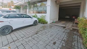 A building with a signboard, a paved entrance, and a white car parked in front. - VOV Hotels Vijayapura (Bijapur)