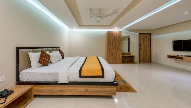 A modern bedroom with a bed, a ceiling fan, a wardrobe, and a TV. - VOV Hotels Vijayapura (Bijapur)