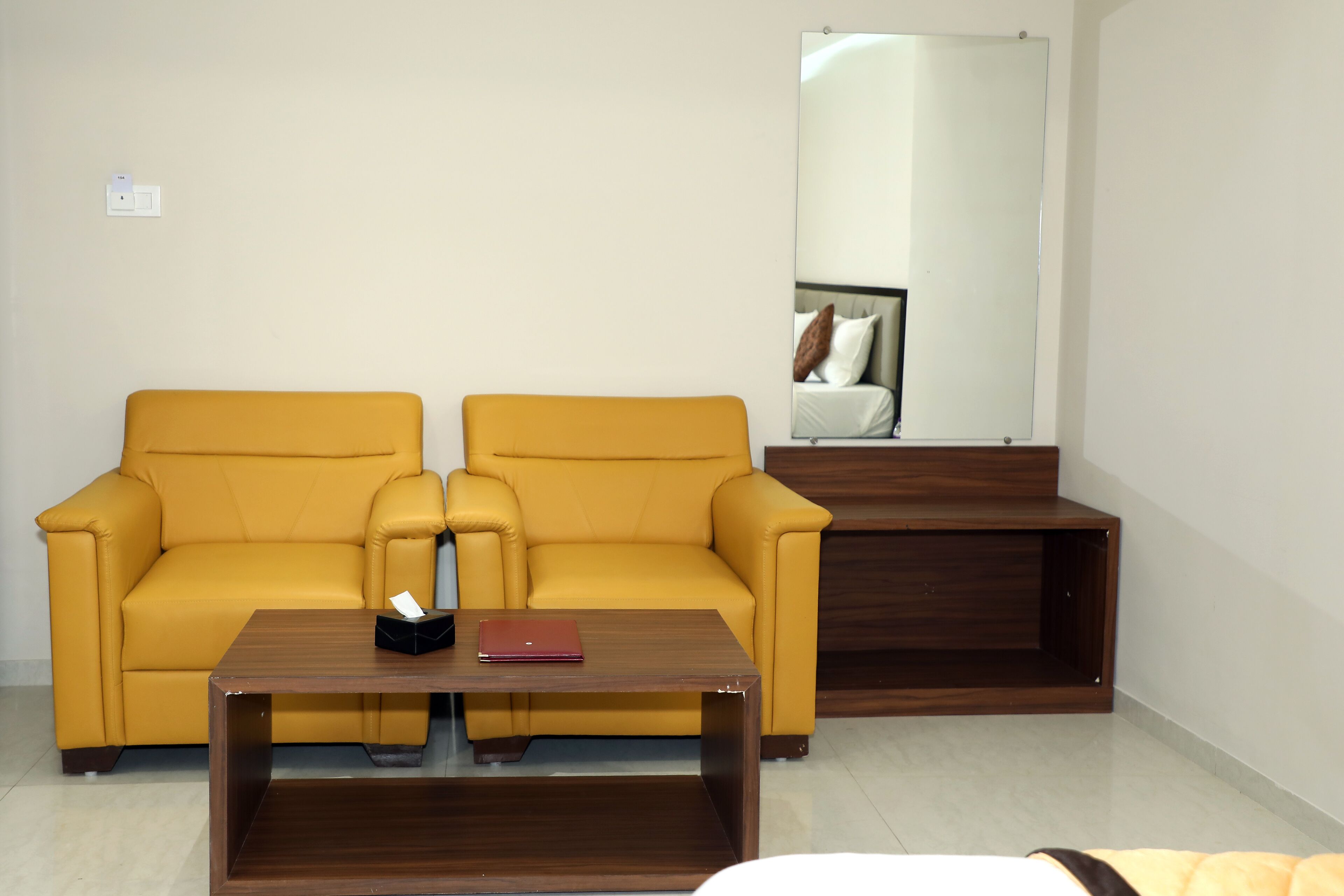 Una habitación con un sofá amarillo, una mesa de centro de madera y un espejo en la pared.