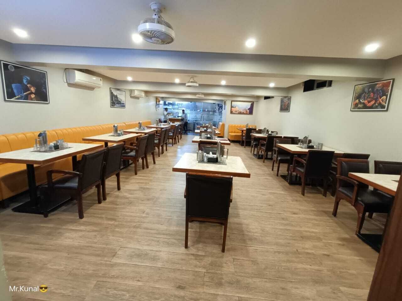 A restaurant with multiple tables and booths, a central serving area, and artwork on the walls.