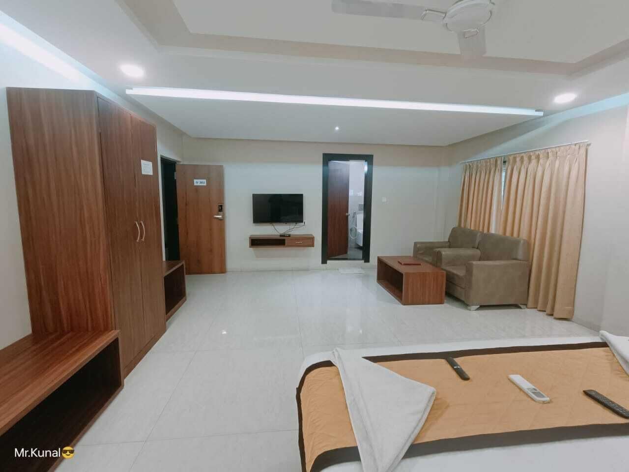 Una habitación de hotel moderna con una cama, un sofá, un televisor y un armario.