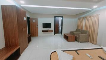 Una habitación de hotel moderna con una cama, un sofá, un televisor y un armario.