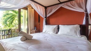 A bed with white linens, a canopy, and a view of palm trees. - Rising Star Dive Resort (Karangasem)