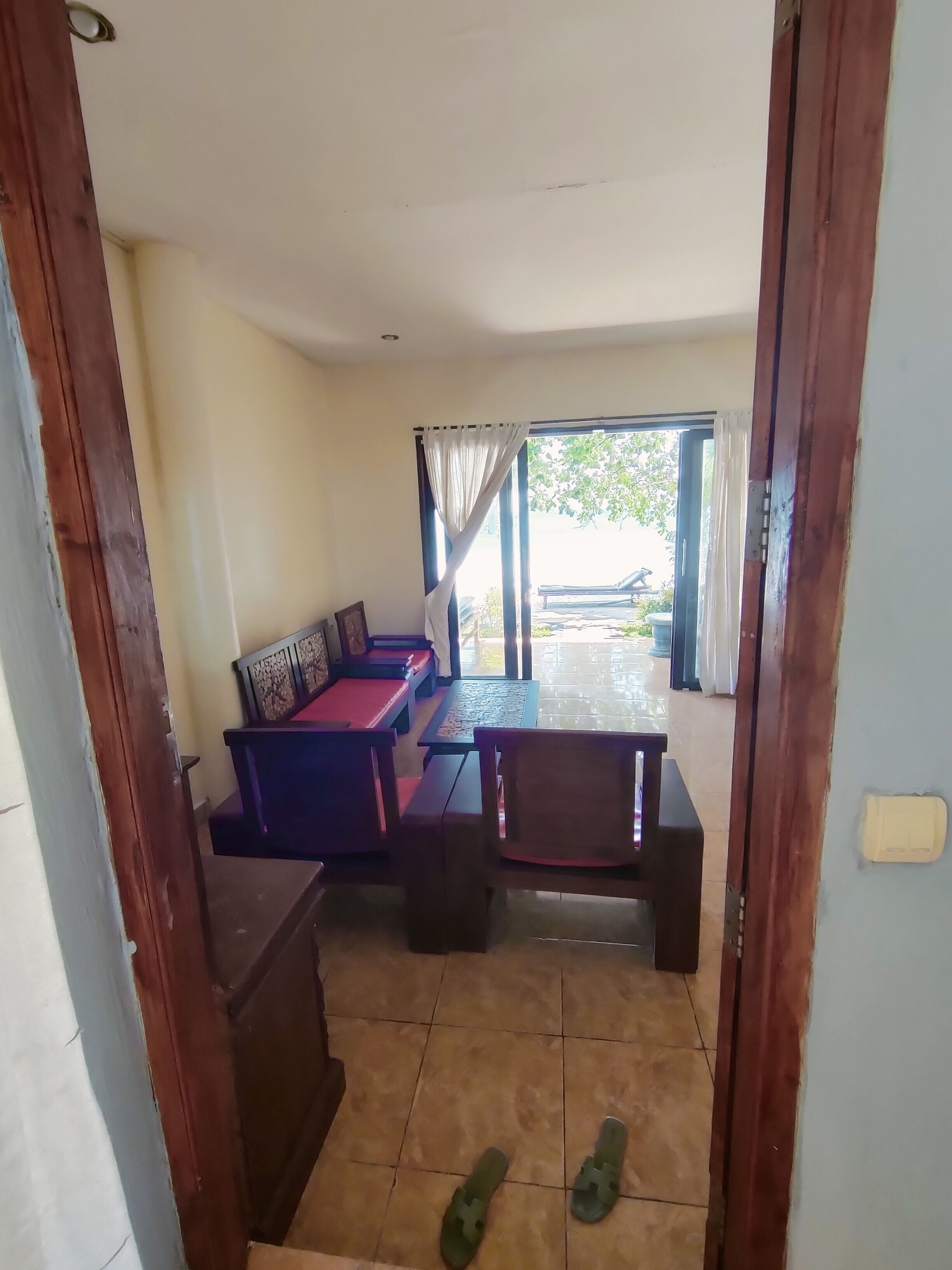 A room with a sofa set, a dining table, and a view through a window.