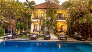 A poolside area with lounge chairs and a building with balconies. - Rising Star Dive Resort (Karangasem)