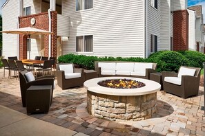 Eine Terrasse mit einem Steinkamin, Gartenmöbeln und einem überdachten Sitzbereich.