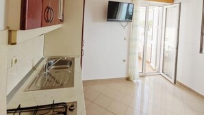 A kitchen with a gas stove, a microwave, and a TV mounted on the wall. - House in a quiet environment in the immediate vicinity  of the beach (Stara Novalja)