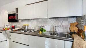 Una cucina moderna con mobili bianchi, fornello a gas, lavello e una schiena di cucina decorativa.