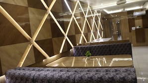 A modern interior with a geometric wall design, seating area, and a ceiling fan. - Signum CityScapes The Royal Castle Plaza (Rajkot)