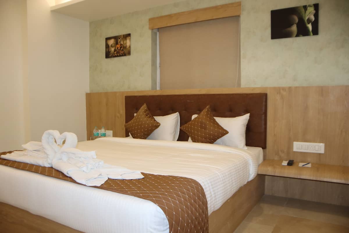 Habitación de hotel con una cama grande, cabecera de madera y mesita de noche con teléfono y control remoto.