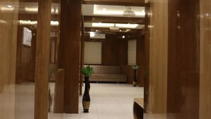 A modern lobby with polished wood paneling, a reception desk, and a seating area. - Signum CityScapes The Royal Castle Plaza (Rajkot)