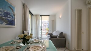 A dining area with a glass table set for four, a sofa, and a radiator. - Gran Torino 17 in Cattolica (Cattolica)