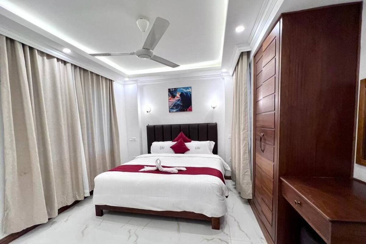 A modern bedroom with a large bed, a ceiling fan, and a wooden wardrobe.