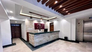 A hotel reception area with a stone counter, wooden ceiling beams, and a tiled floor. - Dune View Hotel (Mombasa)