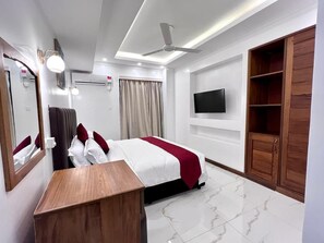 Ein Hotelzimmer mit Bett, Schreibtisch, Wandfernseher und Kleiderschrank.