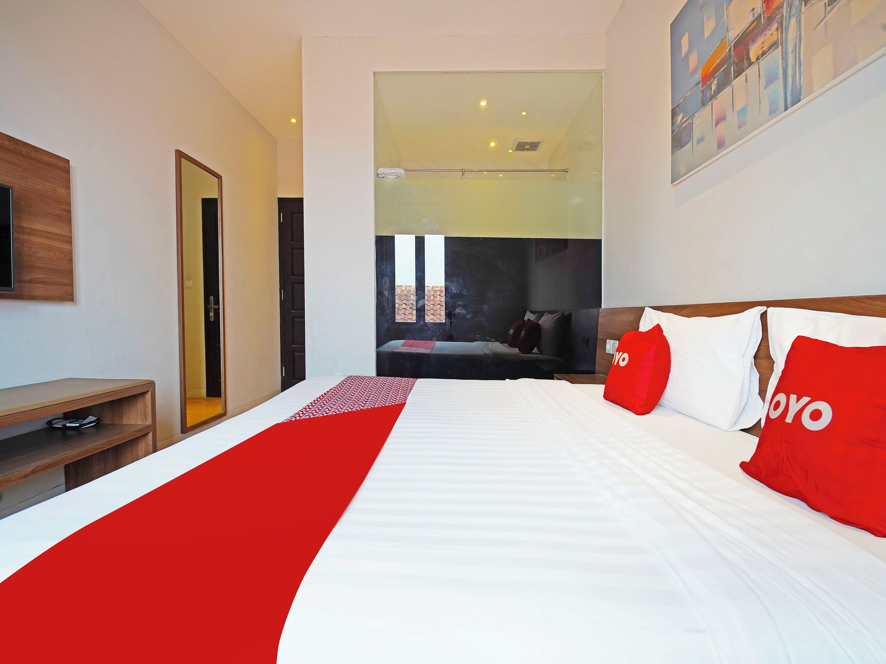 Quarto de hotel com cama, televisão, escrivaninha e vista exterior.