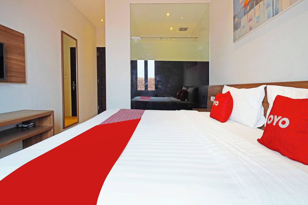 A hotel room with a bed, a TV, a desk, and a view of the outside.