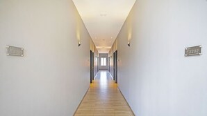 Ein langer, schmaler Korridor mit Holzboden und weißen Wänden. Es befinden sich zwei Durchgänge mit den Nummern 2201 und 2202 an den Wänden.