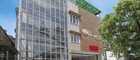 A modern building with a glass facade and a wooden section with a sign that reads "The Regia."