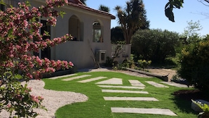 Un jardín bien cuidado con un sendero de piedra que lleva a una casa con techo de tejas rojas.