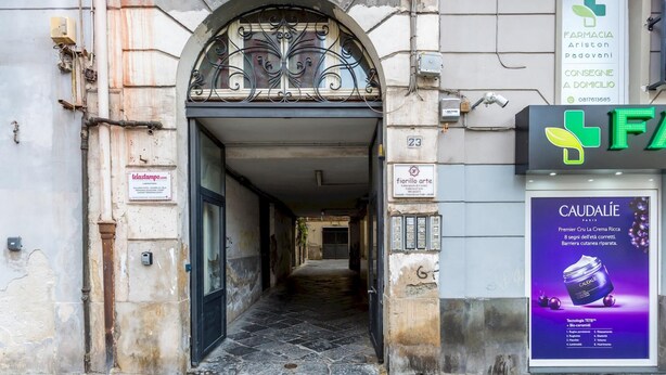 A narrow alleyway with a building entrance featuring a wrought iron gate and a sign for 'fiorillo arte'. - Casa Fiorita Alla Riviera by Napoliapartments (Naples)