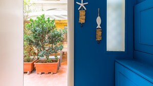A blue door with a window, a potted plant, and two wall decorations (starfish and fish). - Casa Fiorita Alla Riviera by Napoliapartments (Naples)