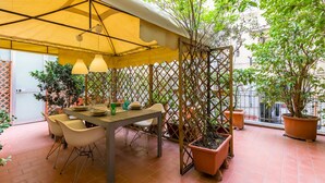 An outdoor patio with a table and chairs, surrounded by potted plants and a yellow canopy. - Casa Fiorita Alla Riviera by Napoliapartments (Naples)