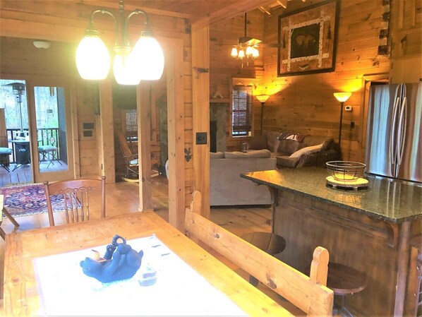 A cozy cabin interior with a wooden dining table, a bar area, and a sofa.