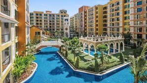 Un complejo residencial con piscina central, varios edificios de apartamentos y un puente que conecta diferentes áreas.