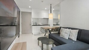 Una sala de estar moderna con un sofá gris oscuro, una mesita redonda y un mueble para televisor.