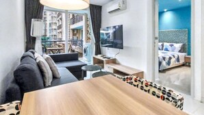Una habitación de hotel moderna con sofá, una mesa de comedor, televisor y cama.