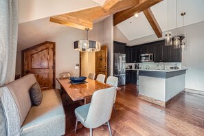 A modern kitchen with dark cabinets, stainless steel appliances, and a wooden dining table with chairs. - The Sebastian, Award Winner!  Vail Village-Ros, Hot Tub, Pool, (Gondola 1) Ski Storage (Vail)