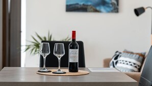 Une bouteille de vin et deux verres sur une table, dans une pièce donnant sur la mer.