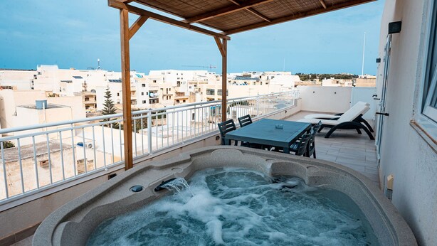 Une terrasse sur le toit avec un jacuzzi, des sièges extérieurs et une vue sur le paysage urbain.