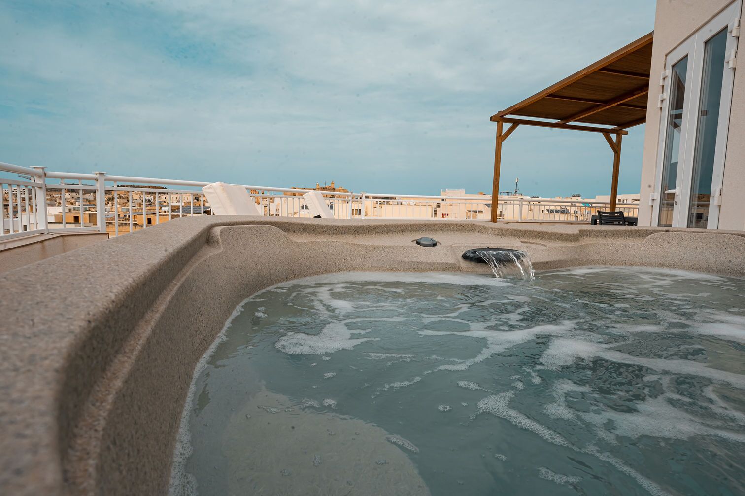 A hot tub on a balcony with a view of the city.