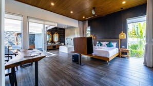 Een moderne hotelkamer met een houten plafond, een groot bed met televisie, een zithoek met een houten tafel en uitzicht op het omliggende landschap.