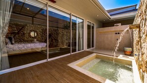 Een moderne spa-ruimte met een stenen muur, een houten vloer en een klein zwembad.