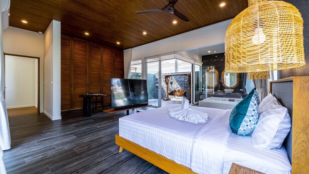 Een moderne slaapkamer met een groot bed, een televisie en een plafondventilator.
