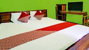 A neatly made bed with a red and white patterned bedspread, two red pillows, and a wooden headboard.