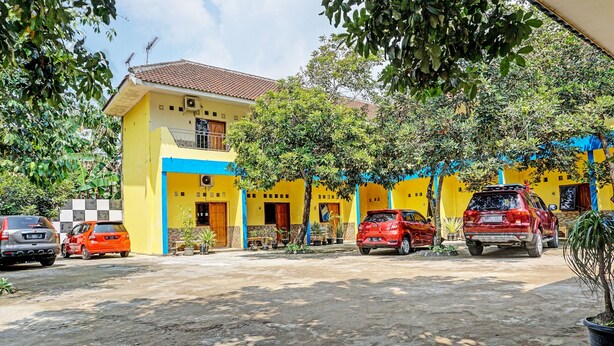 A yellow building with blue accents, parked cars, and potted plants.