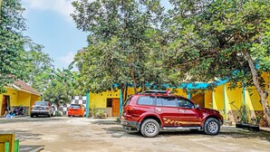 A red SUV parked in a driveway with a yellow building in the background.