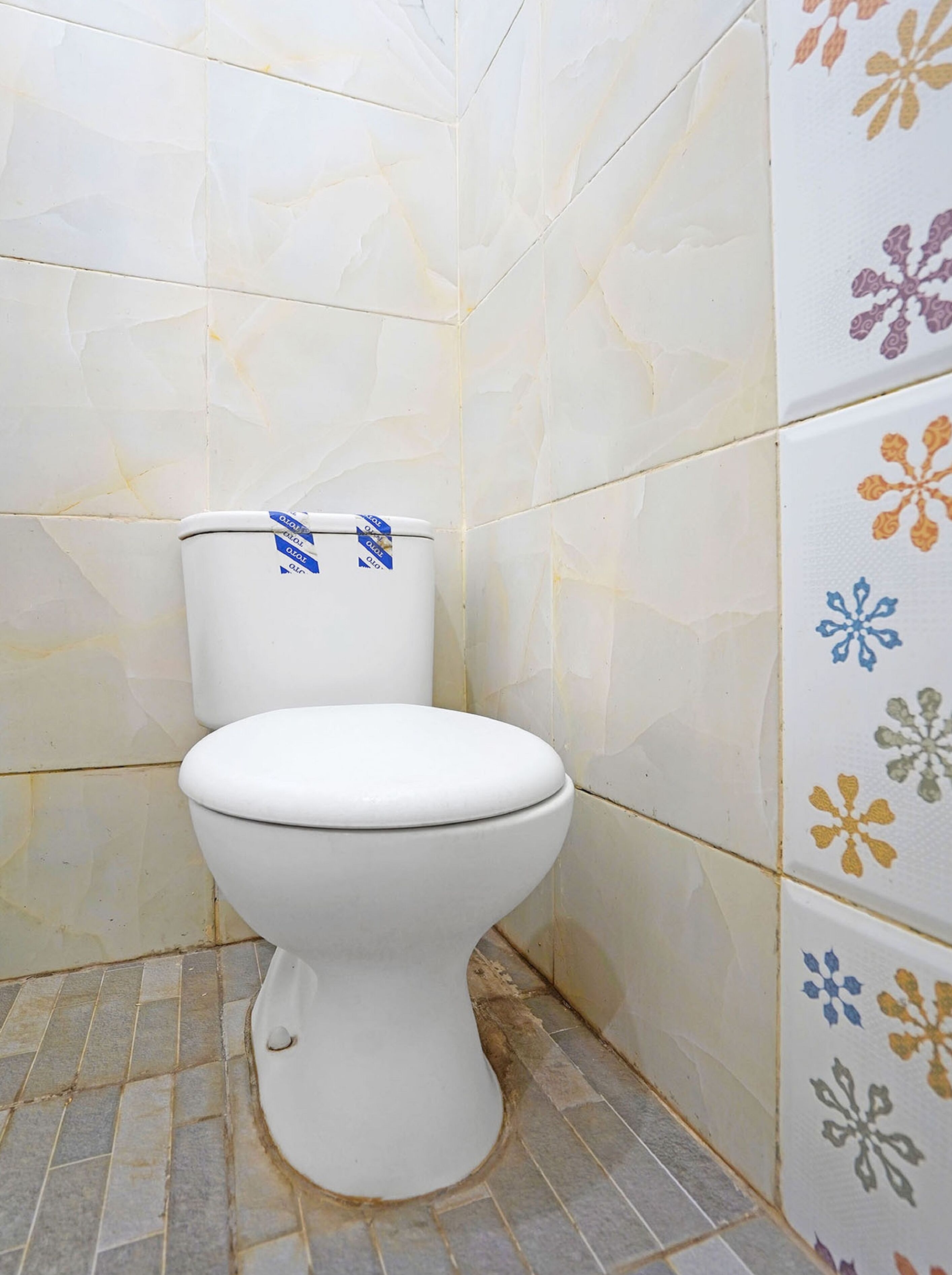 A toilet in a bathroom with patterned tiles on the walls and floor.