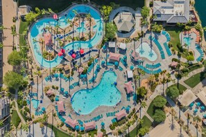 An aerial view of a resort with multiple swimming pools, sun loungers, and palm trees. - Coachella Shuttle, Lazy River: 3BR in Resort (Indio)
